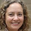 The image displays a pile of mixed household waste on a paved driveway or yard surface. Prominently, there are several large black plastic rubbish bags, some slightly crumpled with a matte finish, containing unknown contents. Near the bags, numerous cardboard boxes are visible, some flattened and others partially collapsed, showing torn edges and corrugated textures. Scattered plastic bottles and containers with transparent and coloured surfaces are mixed among the waste. A few metal and plastic objects, such as a discarded garden tool and a plastic bucket, are also present. The waste appears to be loosely stacked, with some items leaning against each other. In the background, part of a vehicle or waste collection truck may be faintly visible, indicative of an independent rubbish removal service like Big Ben. The environment suggests an outdoor area suitable for private waste handling or on-site clearance, with natural daylight illuminating the scene and casting soft shadows on the textured surface. The scene captures a snapshot of waste awaiting collection, aligning with the context of alternative rubbish removal or disposal methods, emphasizing the importance of proper waste management and debris clearance processes.